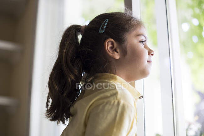 Маленька дівчинка вдома дивиться у вікно. — стокове фото