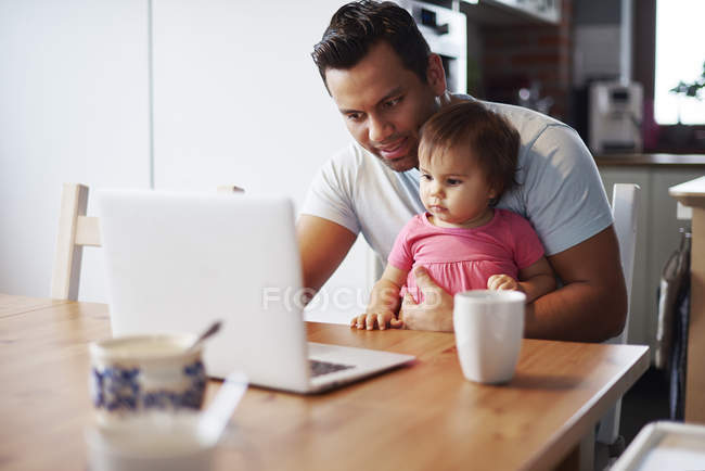 Father with baby girl using laptop on table at home — Stock Photo
