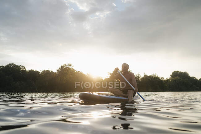 Senior uomo su SUP bordo al tramonto — Foto stock