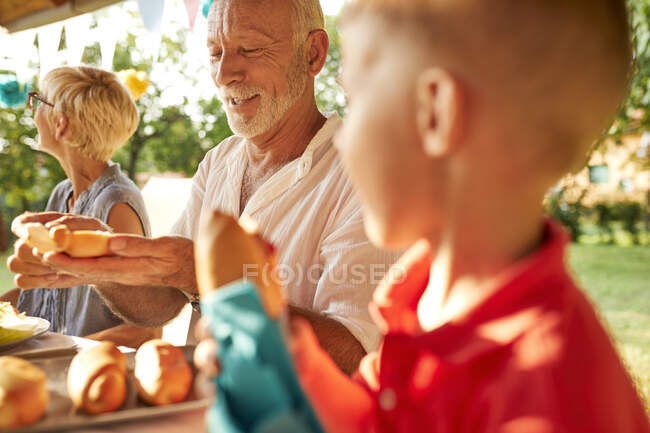 Senior che prepara un hot dog su una festa in giardino — Foto stock