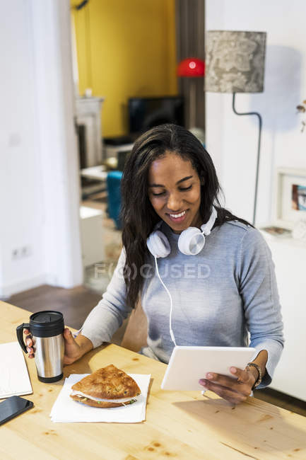 Smiling woman using tablet at table — Stock Photo