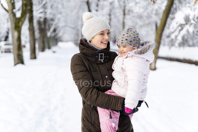Mãe feliz carregando filha na paisagem de inverno — Fotografia de Stock
