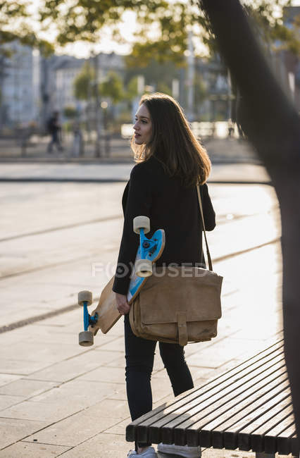 Молода жінка з дошкою в місті на ходу — стокове фото