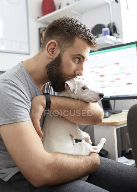 Uomo coccole il suo cane a casa ufficio — Foto stock