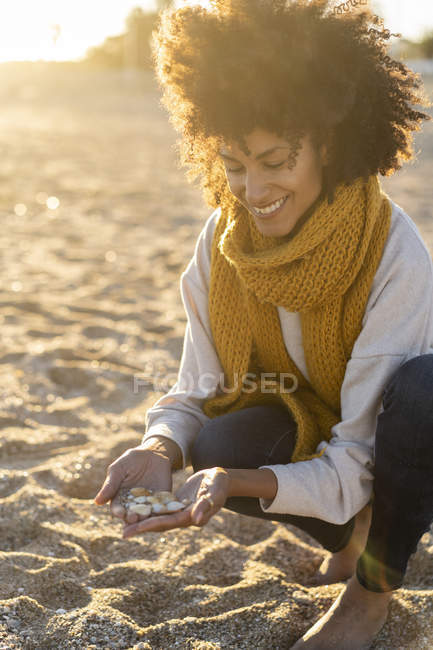 Mujer recogiendo conchas marinas en la playa - foto de stock