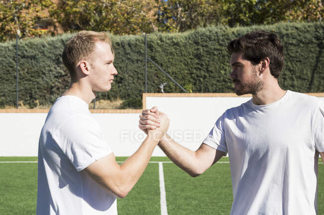 Два футболиста пожимают руки на футбольном поле — стоковое фото