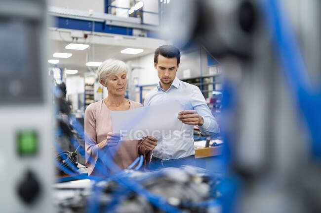 Un homme d'affaires et une femme âgée regardent un plan dans une usine — Photo de stock