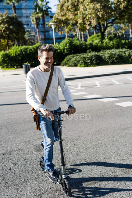 Homem maduro viajando na cidade com sua scooter pontapé, cruzando uma rua — Fotografia de Stock
