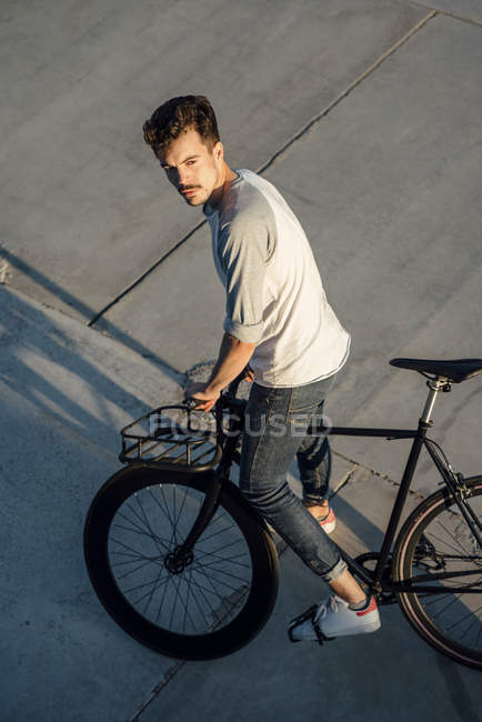 Молодой человек с пригородным велосипедом на бетонных плитах — стоковое фото