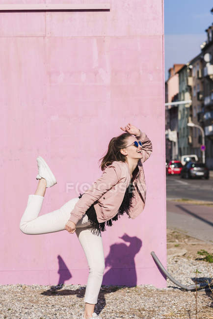Glückliche junge Frau bewegt sich vor pinkfarbener Wand — Stockfoto