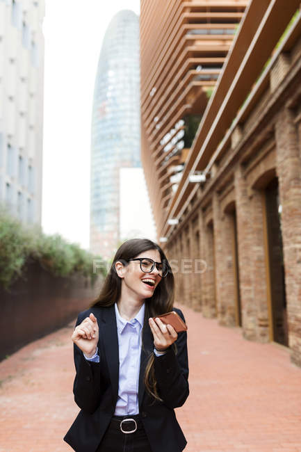 Счастливая молодая деловая женщина держит мобильный телефон в городе — стоковое фото