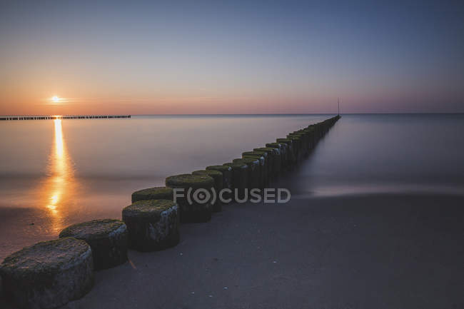 Germany, Mecklenburg-Western Pomerania, Wustrow, Baltic Sea, breakwater at sunset in winter — Stock Photo