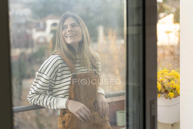 Портрет улыбающейся молодой женщины, отдыхающей на балконе — стоковое фото