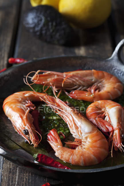 Prawns with hernbs, chili and garlic in iron pan — Stock Photo