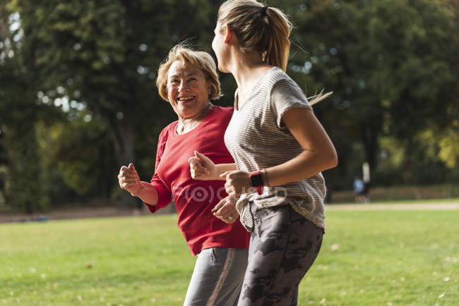 Внучка і бабуся веселяться, бігу разом в парку — стокове фото