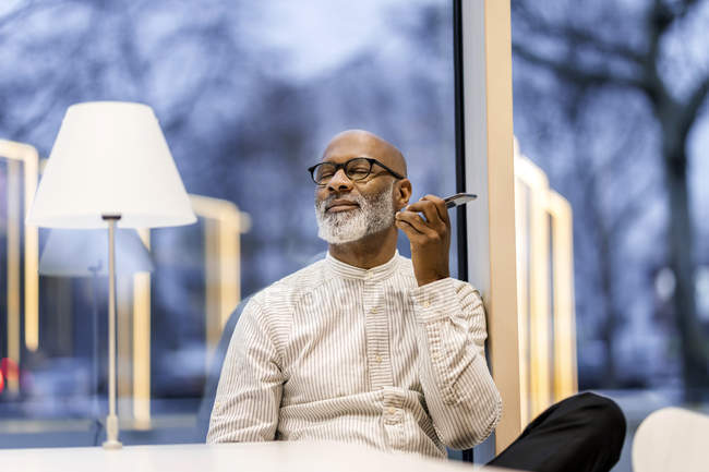 Portrait of mature man listening music with smartphone — Stock Photo