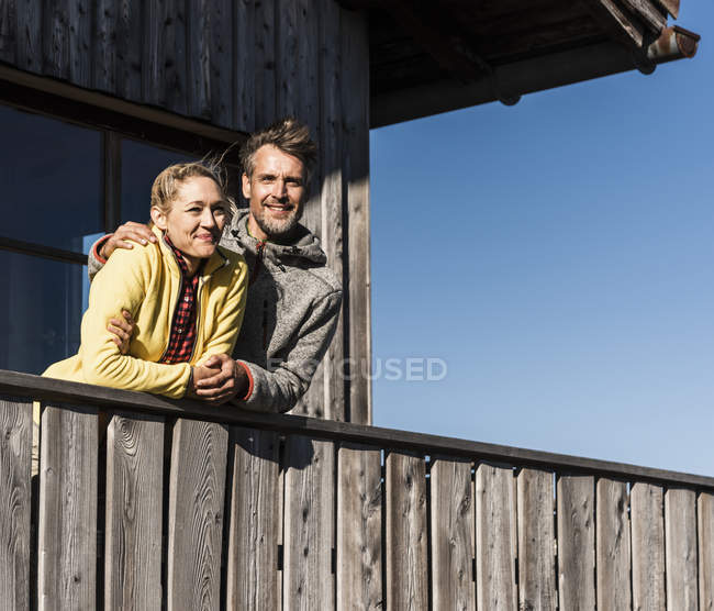 Paar lehnt auf Balkon einer Berghütte, Arme um den Hals — Stockfoto