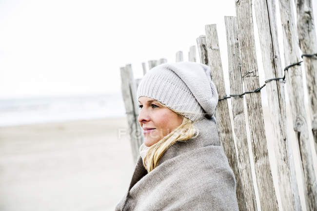 Улыбающаяся женщина у забора на пляже — стоковое фото