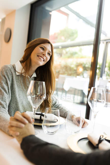 Smiling woman holding hands with man in a restaurant — Stock Photo