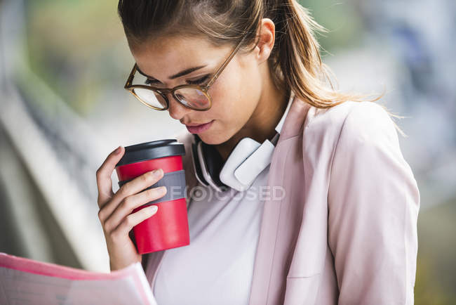 Porträt einer jungen Geschäftsfrau, die Dokumente liest und eine Kaffeetasse hält — Stockfoto