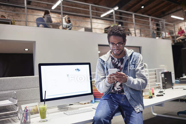 Молодий чоловік працює в креативній стартап-компанії, використовуючи смартфон. — стокове фото