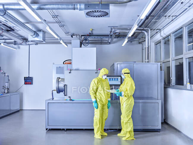 Chimici che lavorano nel laboratorio industriale, indossando indumenti protettivi nella stanza bianca — Foto stock