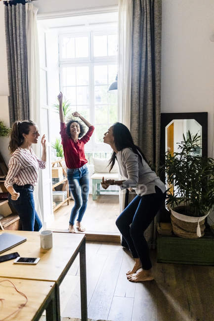 Three women at home having a party and dancing — Stock Photo
