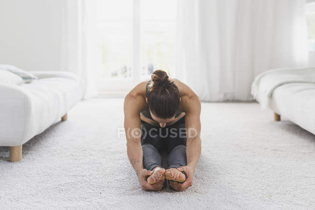 Donna seduta sul pavimento che pratica yoga — Foto stock