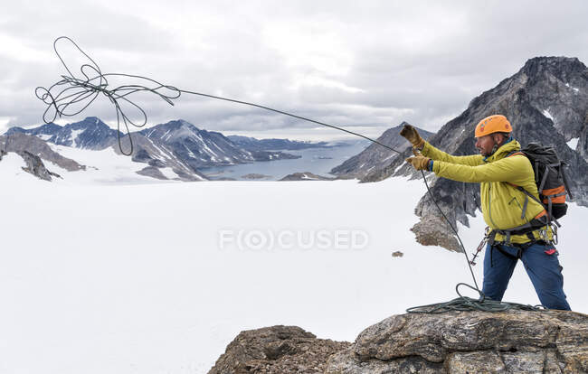 Groenlandia, Sermersooq, Kulusuk, Alpi dello Schweizerland, alpinista in cima che lancia funi — Foto stock