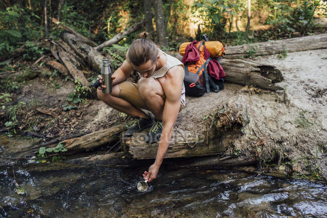 Giovane escursionista che raccoglie acqua dolce in una foresta — Foto stock