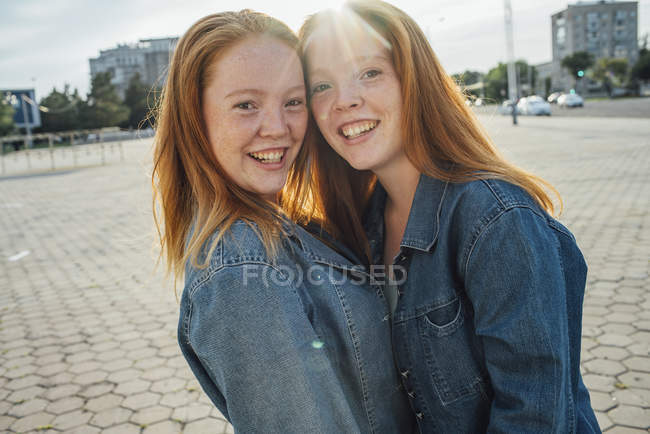 Smiling redheaded twins in the city, sunlight — Stock Photo