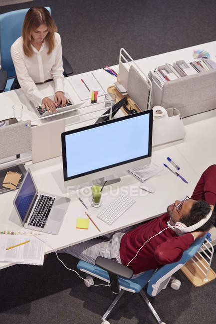 Colleagues working in modern office, man taking a break, listening music — Stock Photo