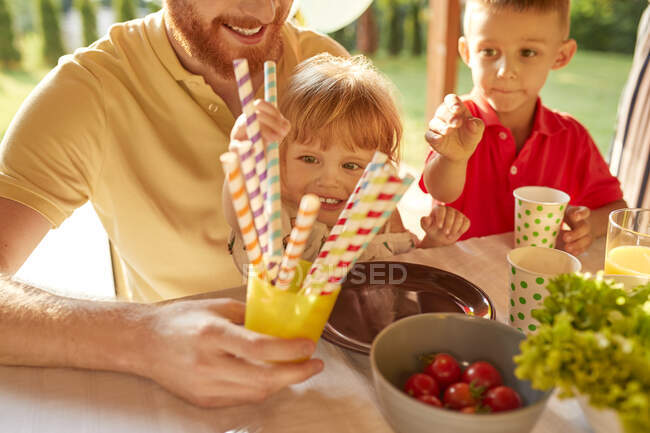 Bambini che prendono cannucce una festa in giardino — Foto stock