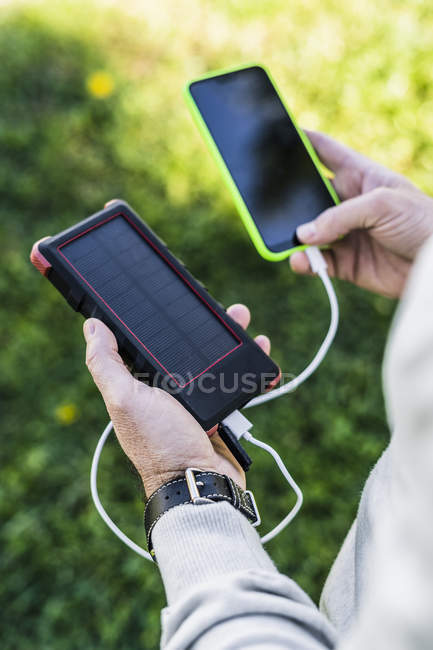 Бізнесмен заряджає свій смартфон банком сонячної енергії — стокове фото