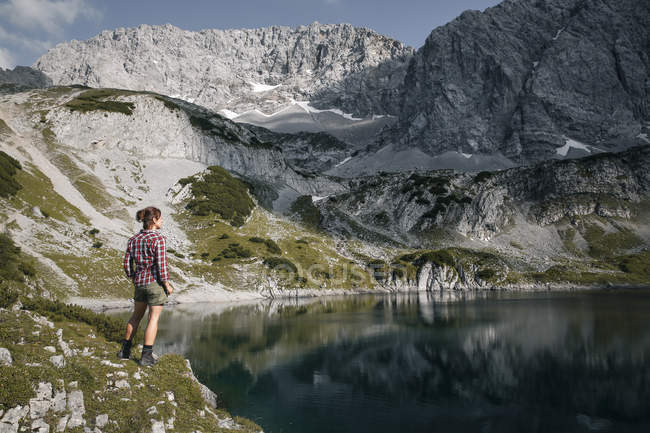 Austria, Tirol, mujer de pie en el lago Drachensee mirando a la vista - foto de stock