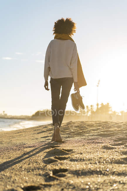 Femme pieds nus sur la plage, portant ses chaussures — Photo de stock