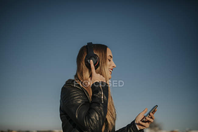 Щаслива молода жінка слухає музику з навушниками на відкритому повітрі — стокове фото