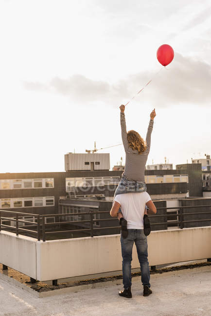 Vue arrière du jeune couple sur la terrasse sur le toit au coucher du soleil — Photo de stock