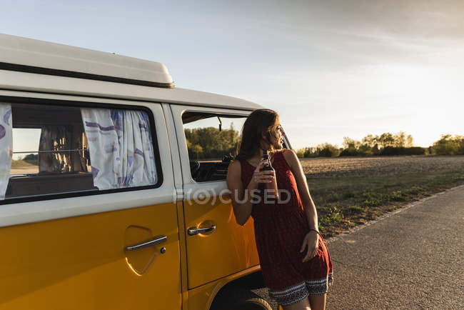 Mujer bonita en un viaje por carretera con su caravana, tomando un descanso al atardecer - foto de stock