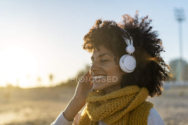 Woman with yellow scarf, listening music on the beach — Stock Photo