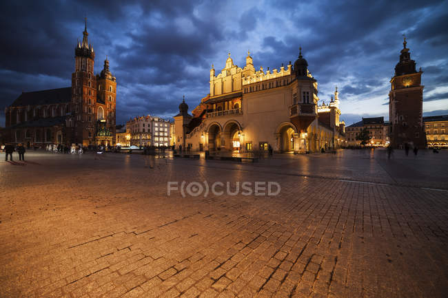 Polonia, Cracovia, piazza principale del centro storico al crepuscolo serale con la chiesa di Santa Maria, il municipio e la torre del municipio — Foto stock