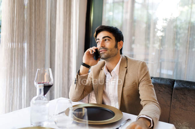 Uomo seduto a tavola in un ristorante a parlare al cellulare — Foto stock