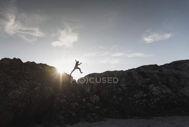 Francia, Bretagna, giovane che salta su una roccia al tramonto — Foto stock