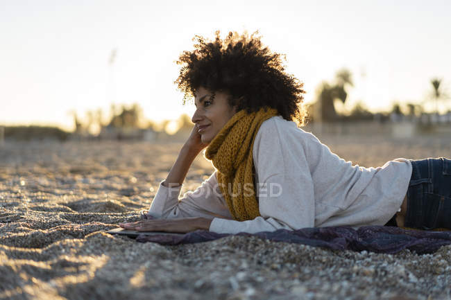 Mujer acostada en la arena, relajada en la playa, leyendo un libro - foto de stock