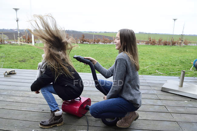 Два друга играют с воздуходувом на террасе — стоковое фото