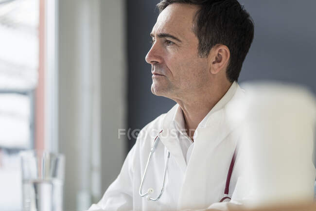 Retrato de médico atencioso na prática médica olhando para os lados — Fotografia de Stock