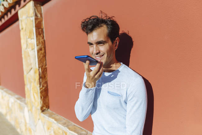 Hombre sonriente usando el teléfono celular en un día soleado - foto de stock