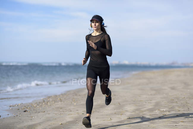 Mujer deportiva corriendo en la playa - foto de stock