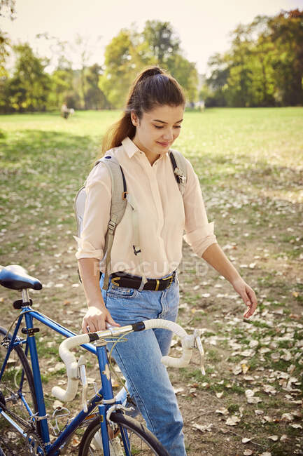 Young woman with bike in park — Stock Photo