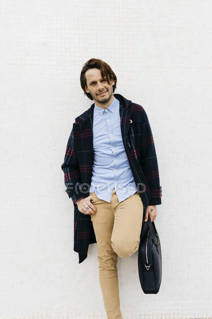 Portrait of confident man with a briefcase standing at a wall — Stock Photo